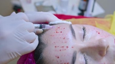 Güzellik ve enjeksiyon konsepti. Klinikte kozmetoloji. Beyaz eldiven giyen deneyimli bir güzellik uzmanı bir kadının yüzüne gerekli aktif malzemeleri enjekte eder.