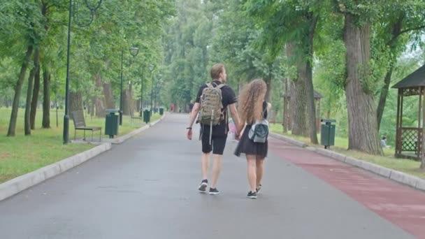 Ein junges paar, ein kerl und ein mädchen, die entlang der böschung im park laufen, sich umarmen, herumalbern, Gefühle füreinander zeigen. — Stockvideo