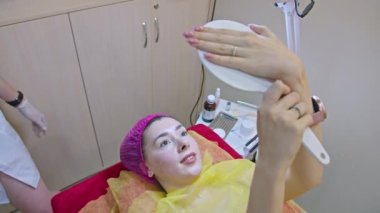 Güzellik kliniği, aynaya bakan bir kadın ameliyattan sonra yüzüne hayran oluyor..