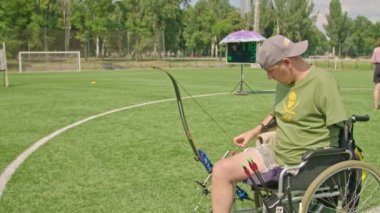 Krivoy Rog, Ukrayna - 24 Temmuz 2021, Invictus Oyunları sırasında Ukraynalı atletler. Bacağı olmayan bir sporcu ve koluyla yayı vuruyor, yayı dişleriyle çekiyor.