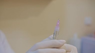 Kozmetik uzmanlarının makro görüşü pembe eldivenler veriyor. Kozmetik malzemelerini yaşlanma önleyici yüz dolgusu enjeksiyonu için şırıngayla karıştırıyorlar. Güzellik enjeksiyon prosedürü.
