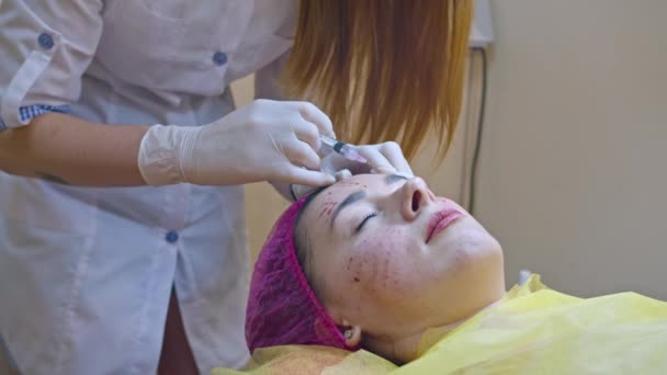 Beauty and injection concept. Cosmetology in the clinic. An experienced beautician wearing white gloves injects a subcutaneous injection with the necessary active ingredients into a womans face for — Stock Video