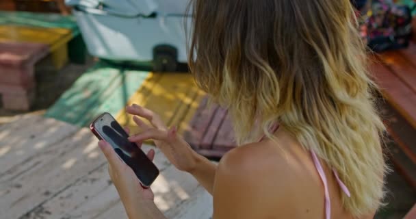 Rubia chica utiliza el teléfono, corre su dedo a través de la pantalla — Vídeo de stock