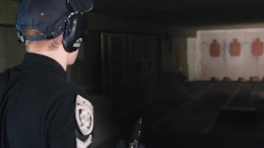 Krivoy Rog, Ukrayna - 06.11.2021: Polis tetikçisi özel bir atış poligonunda bir tabanca eğitmeniyle saate karşı ateş etmek için eğitilmiştir..