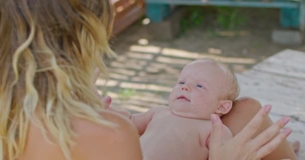 Une jeune mère joue avec un bébé de 3 mois le tenant sur les bras, l'enfant sourit à sa mère, le bébé apprend le monde. — Video