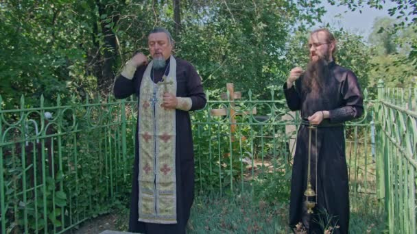 Krivoy Rog, Uktaine 08.10.2021 un prêtre orthodoxe et son assistant lisent une prière au cimetière et effectuent une cérémonie — Video