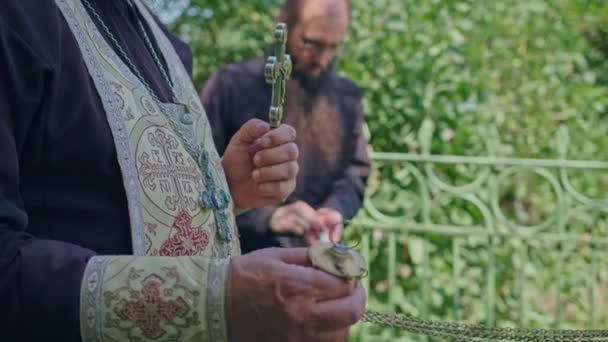 Krivoy Rog, Uktaine - 08.10.2021 um padre ortodoxo e seu assistente lêem uma oração no cemitério e realizam uma cerimônia — Vídeo de Stock