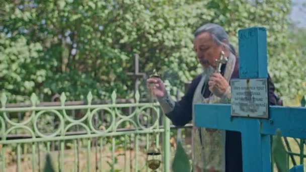 Krivoy Rog, Uktaine - 08.10.2021 seorang pendeta Ortodoks dan asistennya membacakan doa di pemakaman dan melakukan upacara — Stok Video