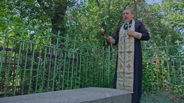 Krivoy Rog, Uktaine - 08.10.2021 한 정교회 사제와 그 의 조수 가 묘지에서 기도를 읽고 의식을 수행 — 비디오