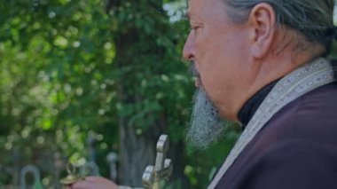 Krivoy Rog, Uktaine - 08.10.2021 Ortodoks rahibi ve yardımcısı mezarlıkta dua okuyup bir tören düzenledi.