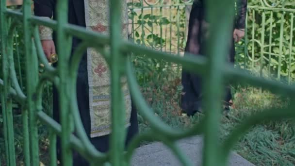 Кривой Рог, Уктейн - 08.10.2021 православный священник и его помощник читают молитву на кладбище и проводят церемонию — стоковое видео