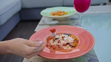 Genç bir kadın somon ve patlıcanla makarna yemekten hoşlanır, sıcak yaz mevsiminde güzel serin bir yerde çatalla yemekten..