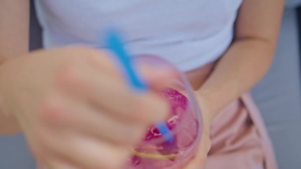 Mano de una joven mujer revolviendo un cóctel en una copa con una paja, primer plano — Vídeos de Stock