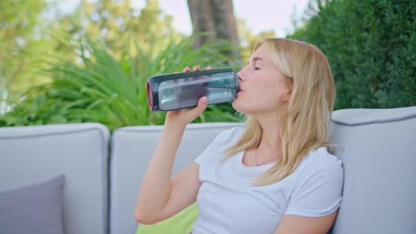 Mujer joven disfrutando de un sorbo de agua en verano caliente, estar en un lugar fresco y hermoso, con una camiseta blanca — Vídeos de Stock