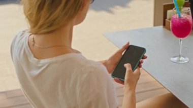 Genç bir kadın telefonda konuşmaktan hoşlanır, biriyle mesajlaşmaktan, harika bir yerde, beyaz bir tişörtle oturmaktan.