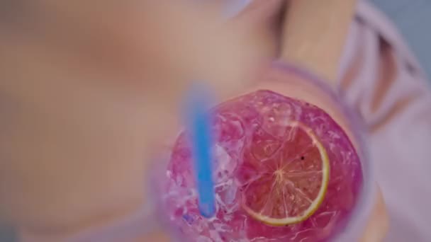 Hand einer jungen Frau, die mit einem Strohhalm einen Cocktail in einem Glas rührt, Nahaufnahme — Stockvideo