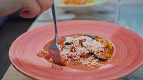En ung kvinna njuter av att äta pasta med lax och aubergine, äta det med en gaffel i en vacker sval plats i varm sommar. — Stockvideo