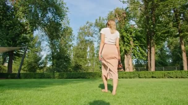 Joven mujer disfruta de relajarse en un maravilloso lugar fresco, verano caliente, paseos y carreras en el césped verde, divertirse, posando para la cámara. — Vídeo de stock