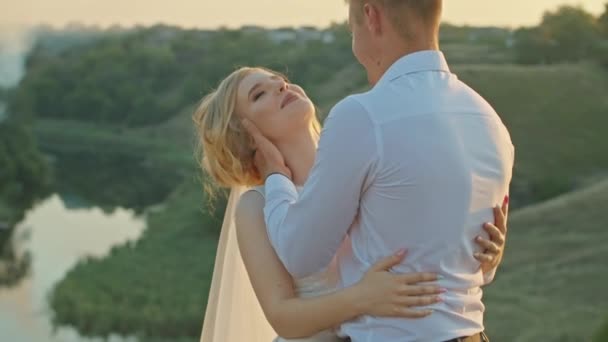 Pareja de boda divirtiéndose al atardecer en una roca cerca del río — Vídeos de Stock
