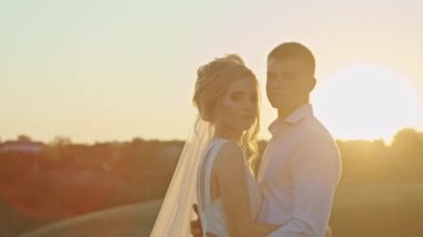 Düğün çifti gün batımında nehir kıyısındaki dağ tepelerinde eğleniyor..