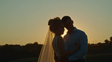 Düğün çifti gün batımında nehir kıyısındaki dağ tepelerinde eğleniyor..