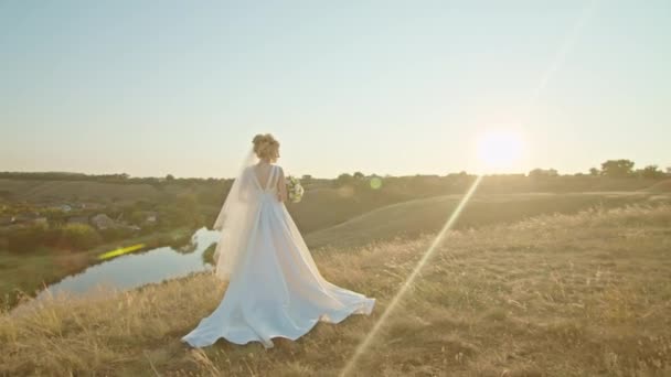Gelukkig jong vrouw bruid bij zonsondergang, staan op een berg heuvel, genieten van een aangenaam uitzicht op de rivier. — Stockvideo