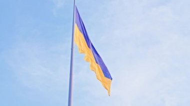 Ukrayna bayrağı, büyük bir bayrak direğinde mavi gökyüzünün arka planında dalgalanan ipek bir bayrak..