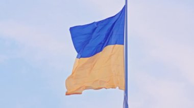 Ukrayna bayrağı, büyük bir bayrak direğinde mavi gökyüzünün arka planında dalgalanan ipek bir bayrak..