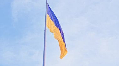 Ukrayna bayrağı, büyük bir bayrak direğinde mavi gökyüzünün arka planında dalgalanan ipek bir bayrak..
