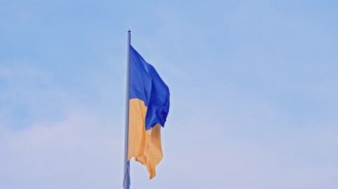 Ukrayna bayrağı, büyük bir bayrak direğinde mavi gökyüzünün arka planında dalgalanan ipek bir bayrak..