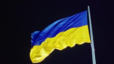 Ukrayna bayrağı, büyük bir bayrak direğinde gece gökyüzünün arka planında dalgalanan ipek bir bayrak..