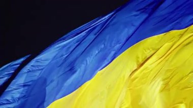 Ukrayna bayrağı, büyük bir bayrak direğinde gece gökyüzünün arka planında dalgalanan ipek bir bayrak..