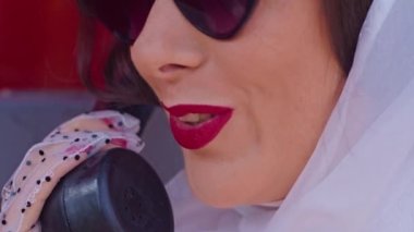 Güzel genç bir bayan, İngiliz tarzı kırmızı bir telefon kulübesinde mutlu bir şekilde konuşuyor. yakın plan.