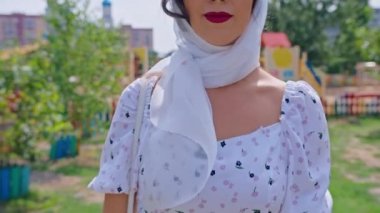 Beyaz elbiseli genç ve mutlu bir kadın sokakta yürüyor.,