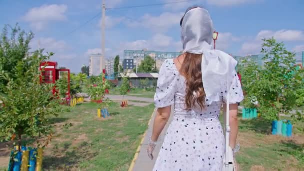 Fiatal boldog nő fehér ruhában sétál végig a sikátorban, pinup, — Stock videók