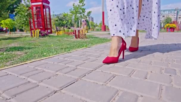 Beyaz elbiseli genç, mutlu kadın sokakta yürüyor, poster, bacaklar, yakın plan. — Stok video