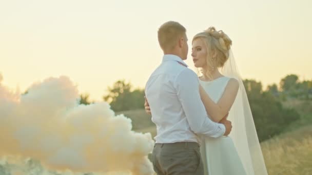 Το ζευγάρι του γάμου επικοινωνεί στο φόντο του ουρανού, η νύφη με ένα μπουκέτο λουλούδια. στέκεται πάνω σε βράχο. — Αρχείο Βίντεο
