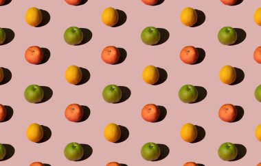 Taze yeşil elma, limon ve mandalina ile yapılmış parlak renkli yaz meyveleri. Pembe pastel arka plan üzerinde düz uzanır, doğrusal, geometrik.