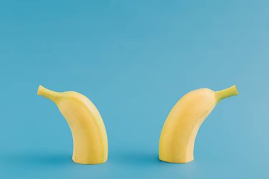 Minimalist tropikal meyve fikri, yarı yarıya taze organik muz ve karşıt mavi arka plan. Yaratıcı yaz meyvesi konsepti, modern yaratıcı düzenleme.