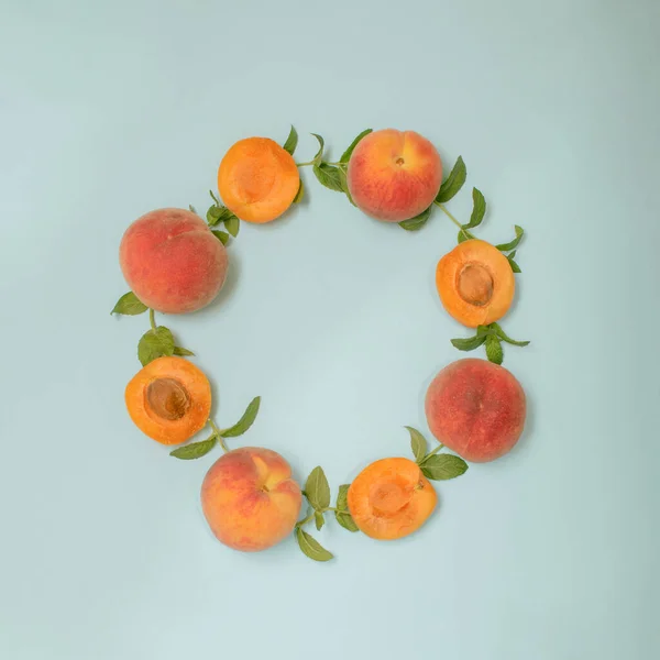 Minimalistic flat lay arrangement with organic raw peach, apricot and mint leaves. Creative summer vibes and fruit circle, aesthetic copy space top view composition.