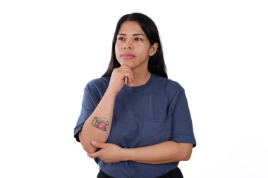 Latin Latin bir kadın esmer ve sakin bir yüz ifadesi, mavi bir tişört giyiyor, beyaz bir arka planda izole edilmiş, kamera dövmesi gösteriyor.