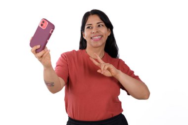 Kırmızı tişörtlü mutlu bir kadın cep telefonunda özçekim yapıyor, beyaz arka planda izole edilmiş.