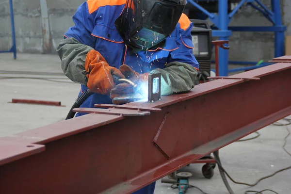 welder works on metal structures at a manufacturing plant