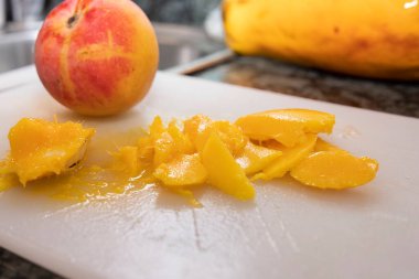 Taze şeftali ve sulu sarı hamur parçaları ev mutfağında beyaz kesim tahtasının üzerinde. Sağlıklı beslenme, organik meyve ve yaz tatlısı hazırlığı kavramı.