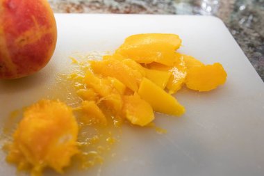 Taze şeftali ve sulu sarı hamur parçaları ev mutfağında beyaz kesim tahtasının üzerinde. Sağlıklı beslenme, organik meyve ve yaz tatlısı hazırlığı kavramı.