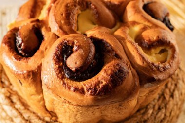 Kremalı çörek ve saman standında buğday kulaklı kuru üzüm. Sıcak tatlı pasta konforu, tazeliği ve geleneksel ev pişirmesini simgeler..