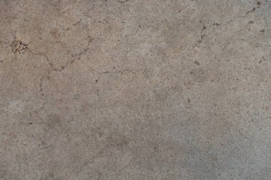 Beige plaster wall with rough texture illuminated by natural sunlight. Architectural detail showing decorative facade surface with sand and cement mix.