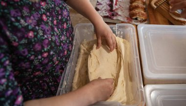 Ev mutfağında plastik bir konteynırda elle yapılan hamur hazırlığı. Yemek pişirme, ev yapımı ekmek, pasta ve geleneksel fırın süreci kavramı.