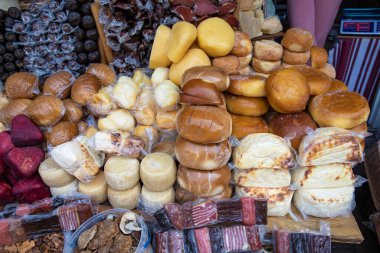 Yerel tarım pazarı masasında çeşitli geleneksel peynirler ve tütsülenmiş et ürünleri sergileniyor. Yerel çiftçilerden ev yapımı organik gıda çeşitleri.