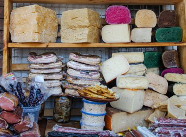 Assorted smoked bacon and colorful cheeses displayed on traditional Ukrainian farm market. Natural homemade organic food products from local farmers.